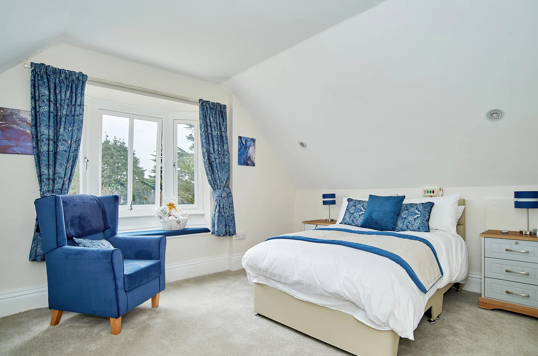 A spacious blue bedroom with a comfortable chair and garden view at Nettlestead