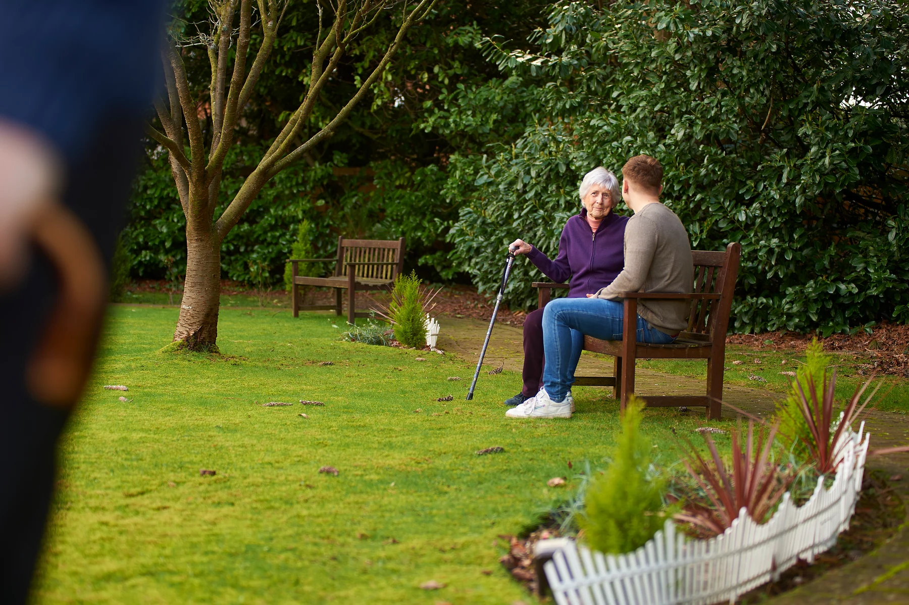 An older woman talking with a companion in the garden
