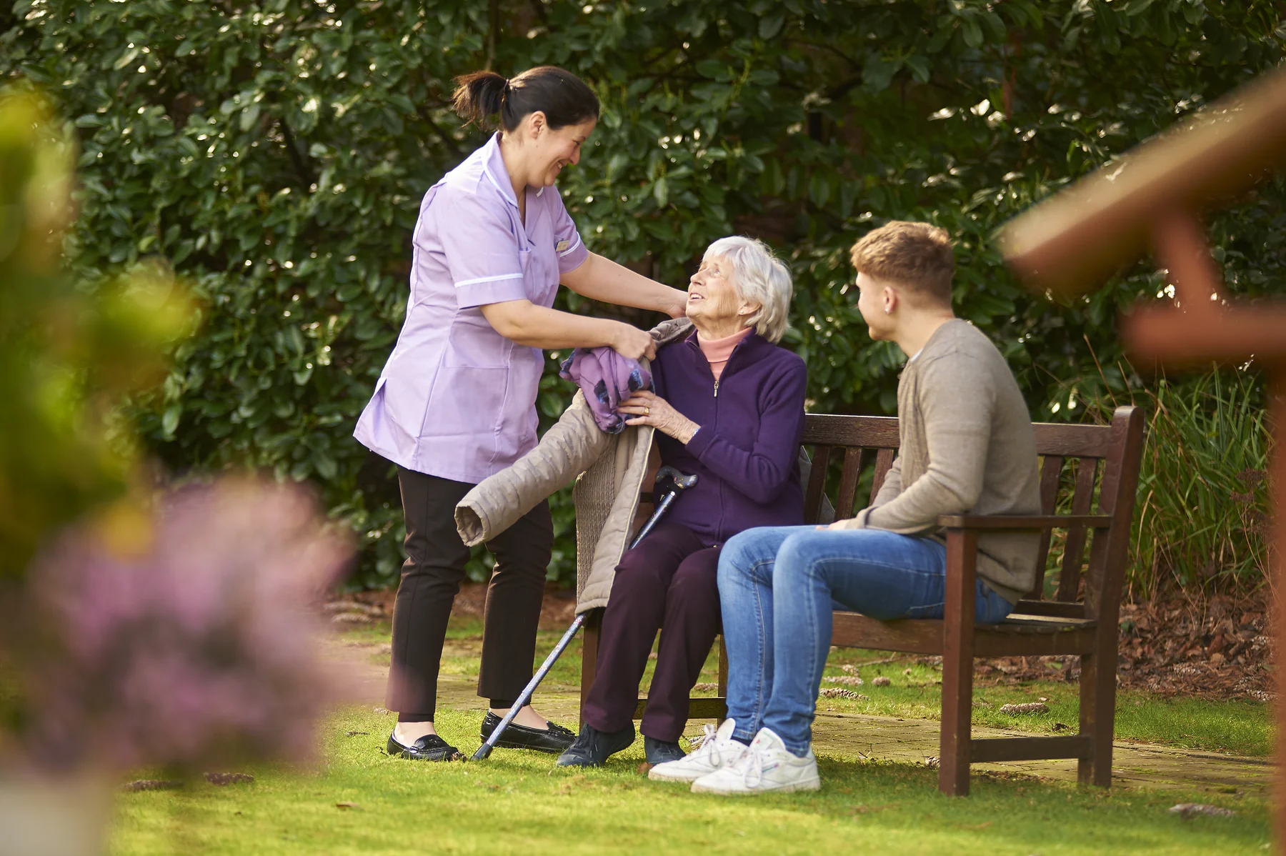 A Nettlestead resident chatting with a member of the care team and a visitor in the garden