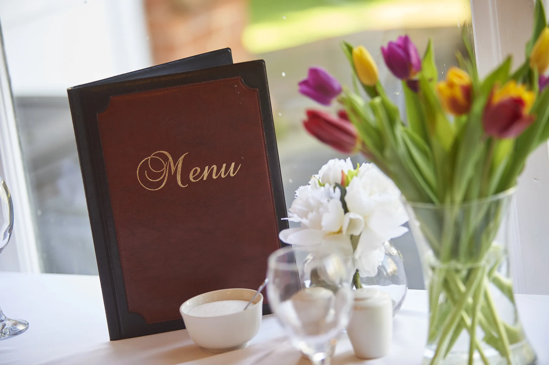 A Nettlestead menu beside flowers on a dining table