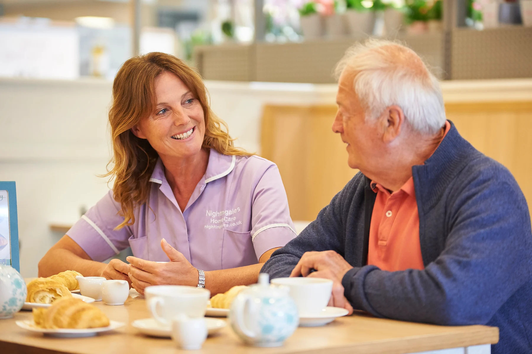 An older man talking with a care professional over tea