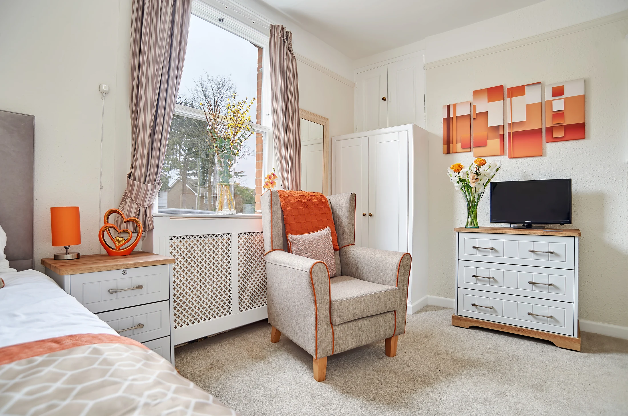 A bright private room at Nettlestead with orange furnishings
