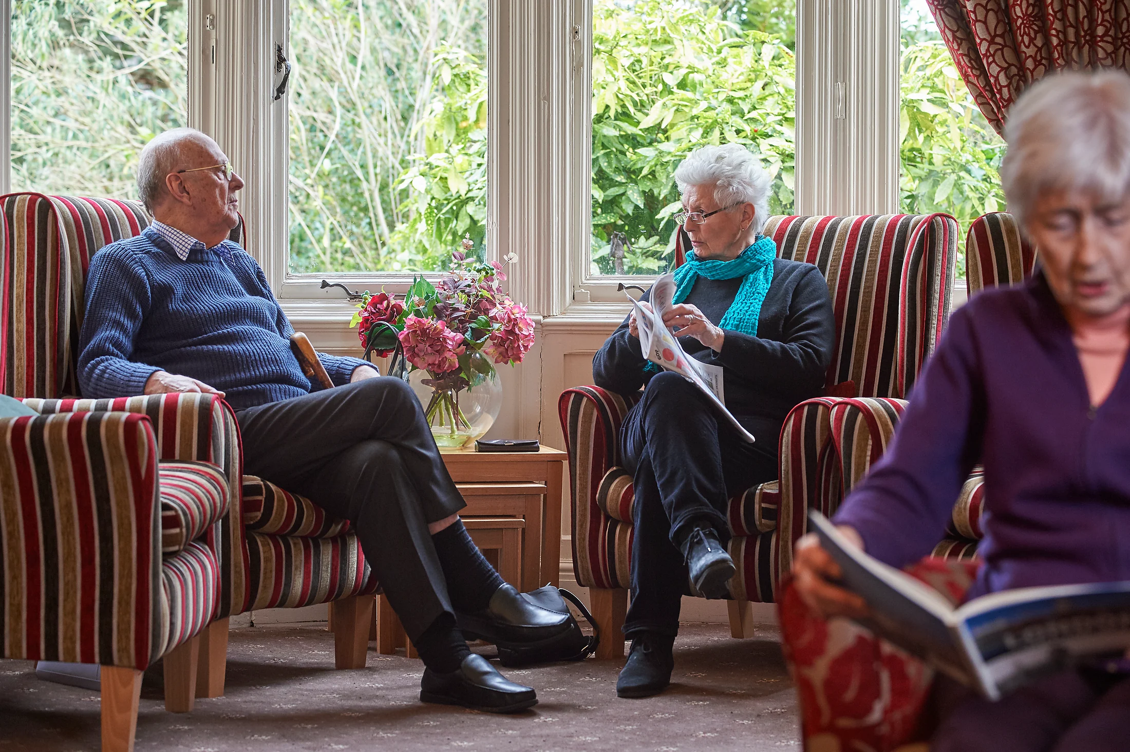 Two older people spending time together in a shared lounge